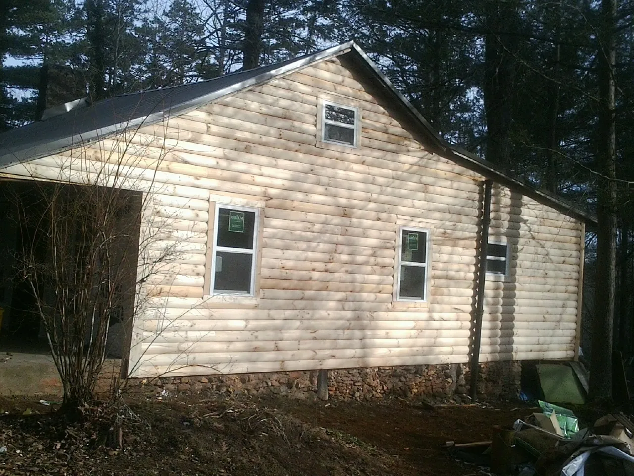 New log siding and dark metal roofing on a gable end in Mableton