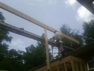 Carpenter setting a ridge beam over a new addition frame — Ice Dam Removal by Roofing Brothers in Mableton