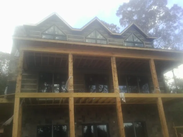 Dormers and porch framing on a large log home under construction — Roof Coating work by our crew in Mableton