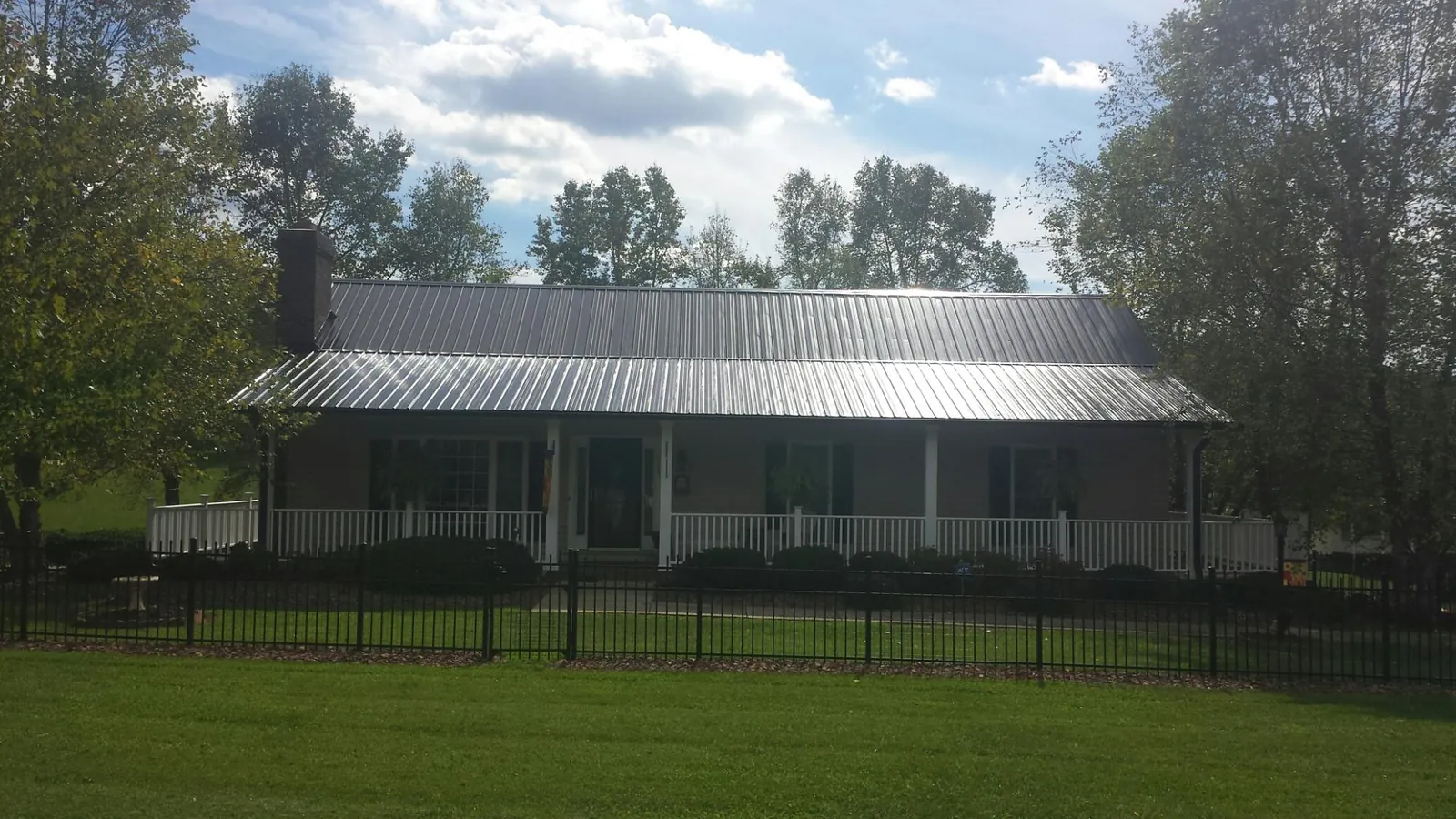 Gray metal roof on a brick ranch with a full width front porch — Gutter Guard Installation work by our crew in Mableton