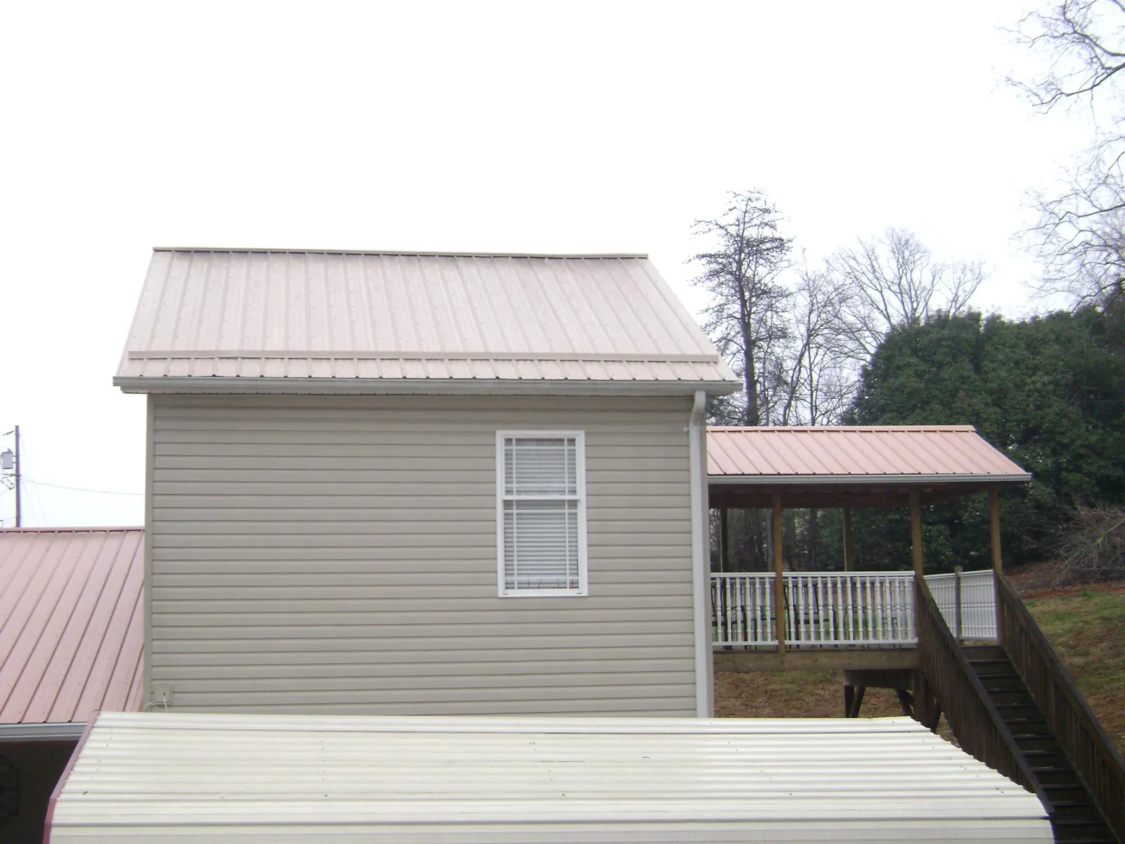 Tan metal roofs on a two story addition and attached porch, from a Roof Replacement job in Mableton
