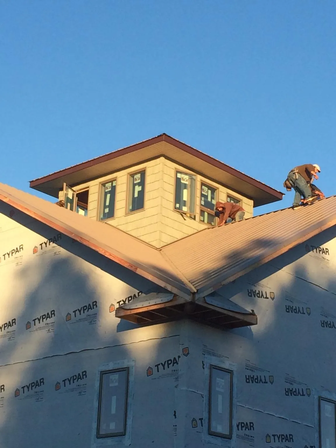 Roofers working around a rooftop cupola on a new metal roof at sunset — Roof Waterproofing in Mableton by Roofing Brothers